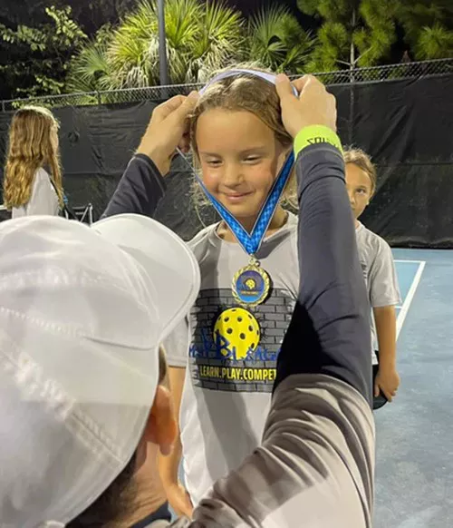 young girl pickleball player being awarded a medal