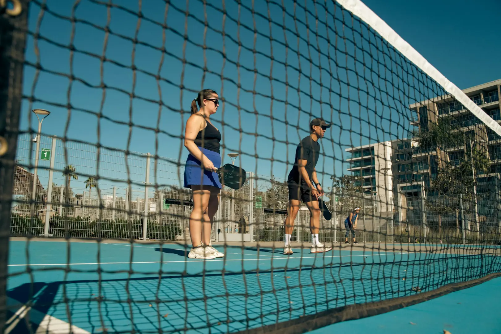 two beginner pickleball players standing behind net